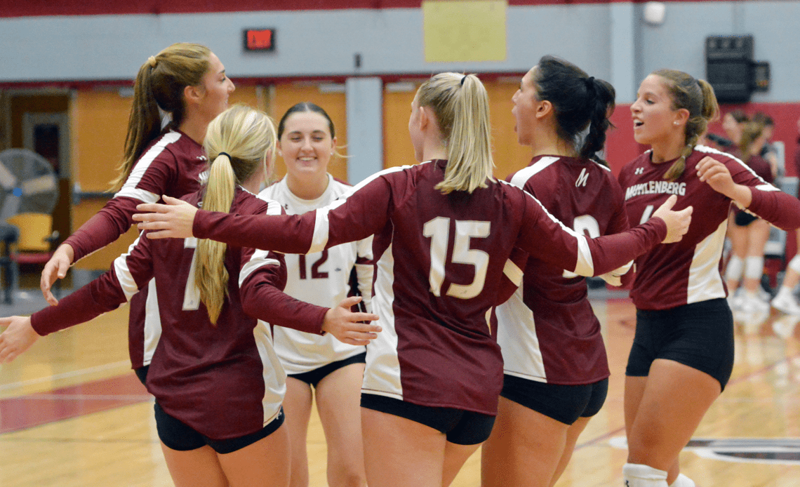 Six Muhlenberg volleyball players wearing red jerseys celebrate a point